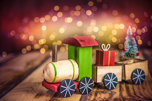 Christmas toy train on wooden floor and defocused lights in the background