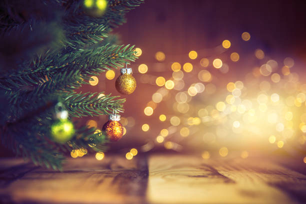 Decorated Christmas Tree Christmas tree decorated with golden & green ornaments on wood floor. Defocused lights in the background. light through trees stock pictures, royalty-free photos & images