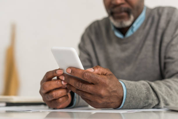 istock cropped view of senior african american man using smartphone while sitting at table 1186313294