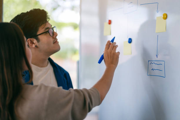 istock Business people looking, discussing and pointing finger at whiteboard 1186315953