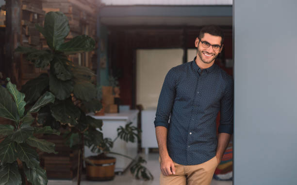 istock Laughing young businessman leaning against a wall in an office 1186318656