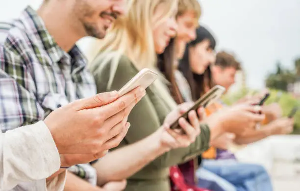 Photo of Group of friends watching smart mobile phones - Teenagers addiction to new technology trends - Concept of youth, tech, social and friendship - Focus on close-up phone, hand