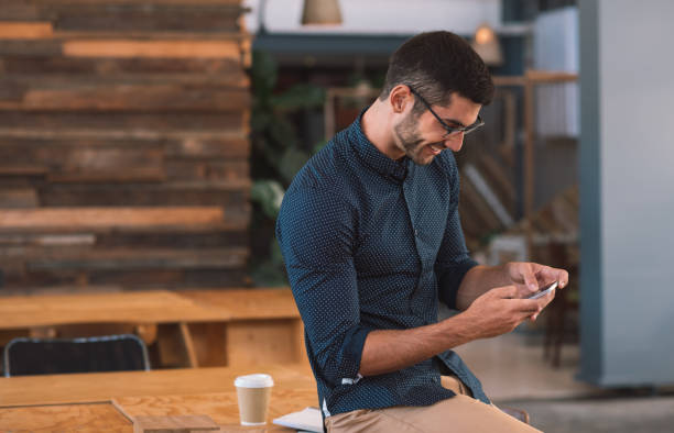 istock Smiling young businessman sending a text message on his cellphone 1186323456