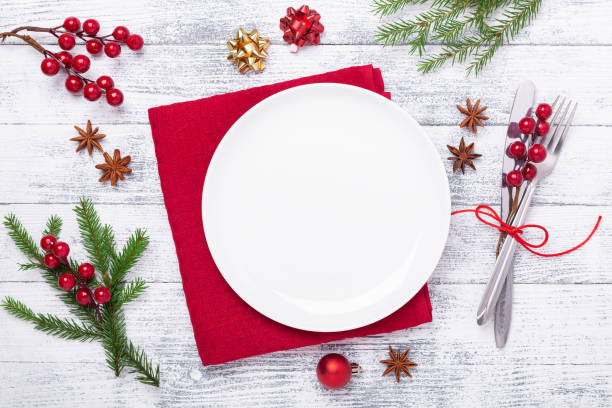 istock Christmas table place setting with empty white plate, cutlery with festive decorations on wooden background 1186323679