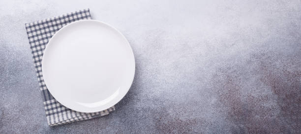 istock Empty white plate and linen napkin on stone background Copy space Top view 1186323781