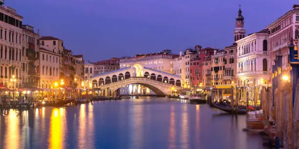 Picturesque panoramic view of famous Rialto Bridge over the Grand Canal in Venice at night, Italy.