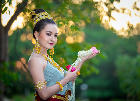 Beautiful woman in Thai traditional costume holding flower garland.