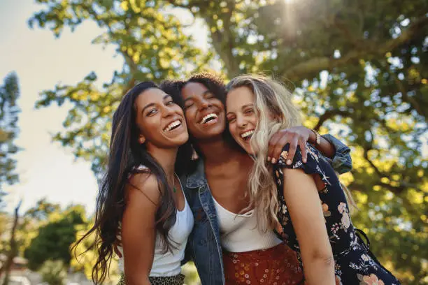 Photo of Portrait of a happy multiethnic group of smiling female friends - women laughing and having fun in the park on a sunny day