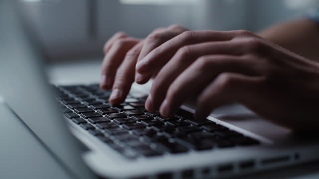Mens hands are typing on the laptop keyboard, close-up.