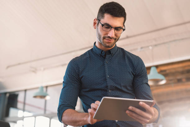 istock Smiling young businessman using a tablet in a modern office 1186325932