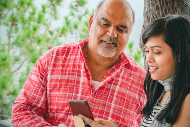 istock Daughter shares a smartphone with her senior, retired father. 1186326076