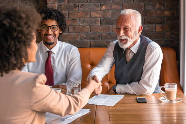 Senior buisnessman shaking hands with woman while sitting in cafe.