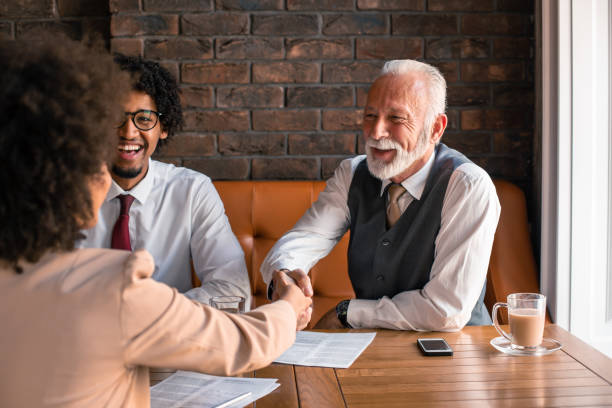 istock Senior buisnessman shaking hands with woman while sitting in cafe. 1186328675