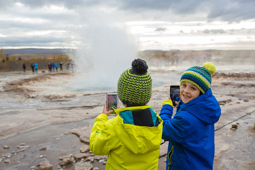 Children, enjoying the eruption of Strokkur Geysir in Iceland autumntime