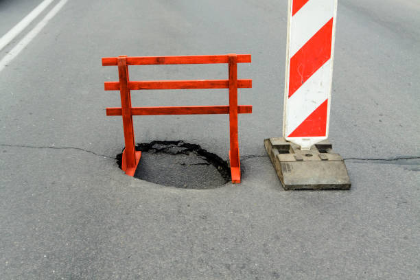 Warning sign and a hole on the road. Dangerous place.
