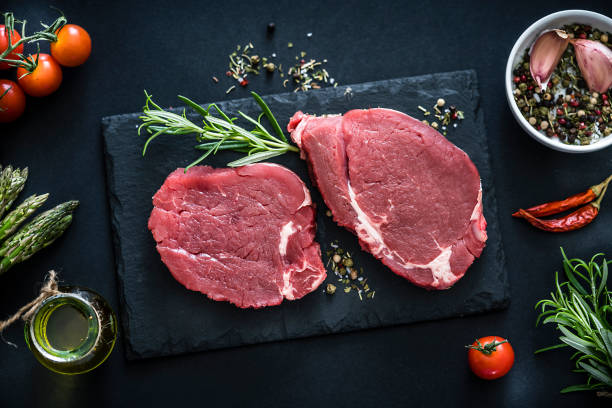 due bistecche di filetto crude girate dall'alto su un tavolo scuro - meat steak filet mignon sirloin steak foto e immagini stock