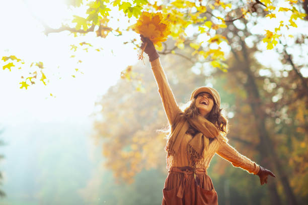 femme heureux avec les lames jaunes se réjouissant à l'extérieur dans le stationnement d'automne - autumn glory photos et images de collection