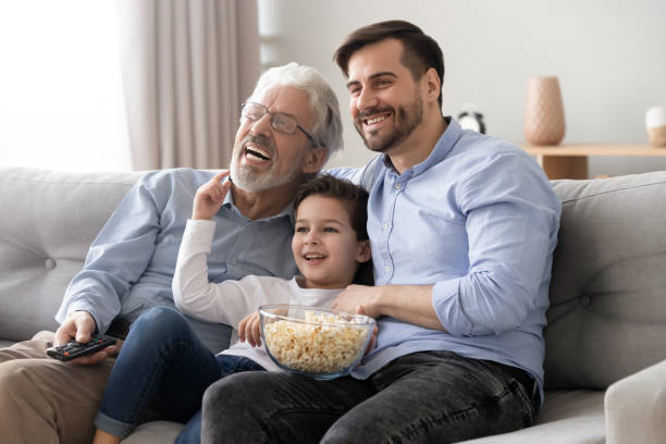 istock Happy three generation men family hold remote control watch tv 1186336137
