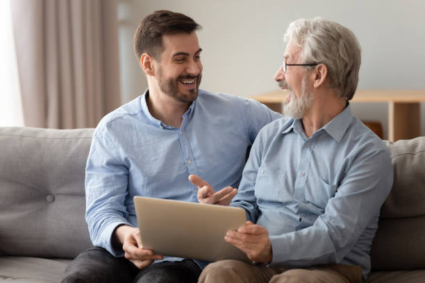 istock Happy excited old father and young son talking using laptop 1186336160