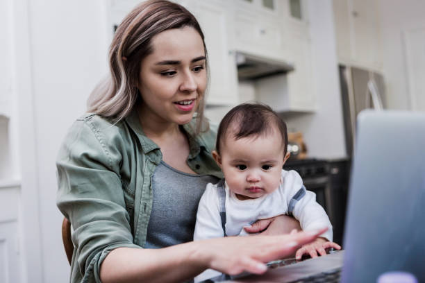 istock Mid adult mother works from home while holding baby 1186336721
