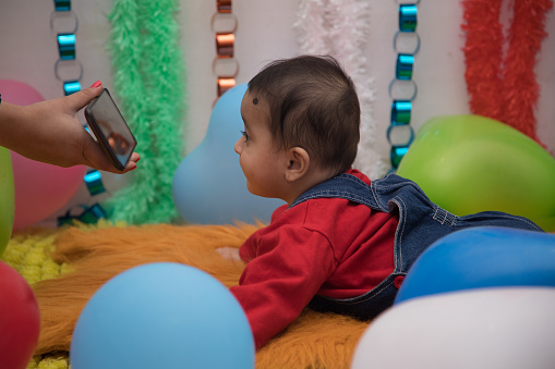 Adorable Indian baby watching movie on smartphone at home
