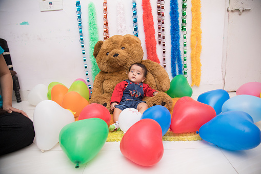 Indian baby girl surrounded by balloons at birthday party
