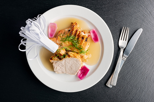 Overhead view of a dish of guinea fowl with pan fried apple and bacon. Colour, horizontal with some copy space, photographed on location at a restaurant on the island of Moen in Denmark.