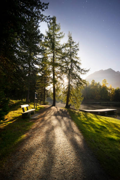 A picturesque Alpine village with charming houses and a tall church steeple, surrounded by vibrant autumn trees and rolling hills under a bright sky. Tranquil and timeless beauty.