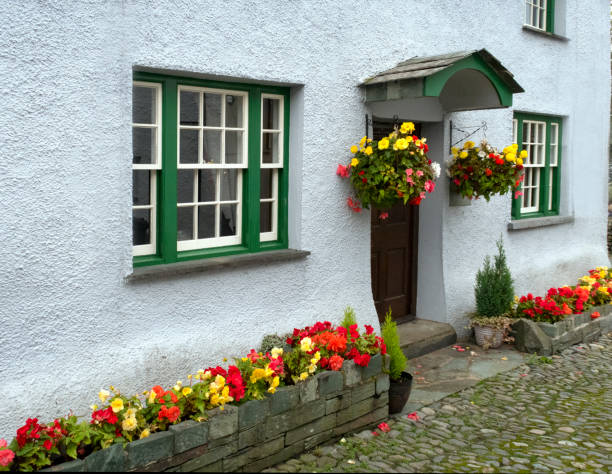colorful flowers in boxes along the street and in hanging pots, in front of a cottage in downtown Hawkshead, England