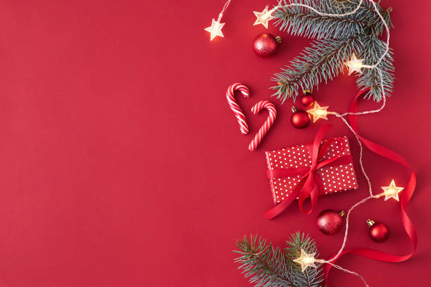 istock Flat lay border with branches spruce,christmas red balls and gift box on a red background 1186348390