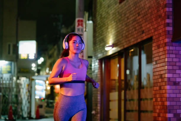 young female athlete running in city at night - night running imagens e fotografias de stock
