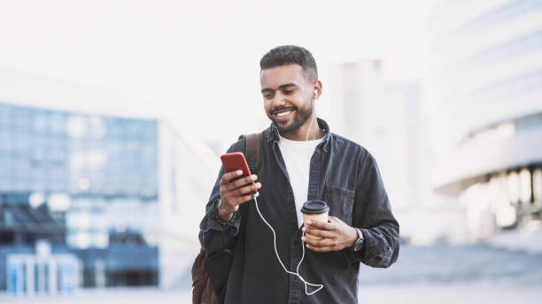 Cheerful young man using smart phone in a city