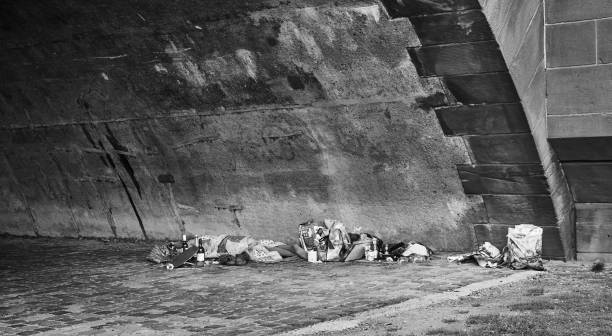 Sleeping homeless people with their household effects in platic bags under a bridge, coarse-grained black and white developed Frankfurt, Germany, October 2., 2019: Sleeping homeless people with their household effects in platic bags under a bridge, coarse-grained black and white developed tramp home stock pictures, royalty-free photos & images