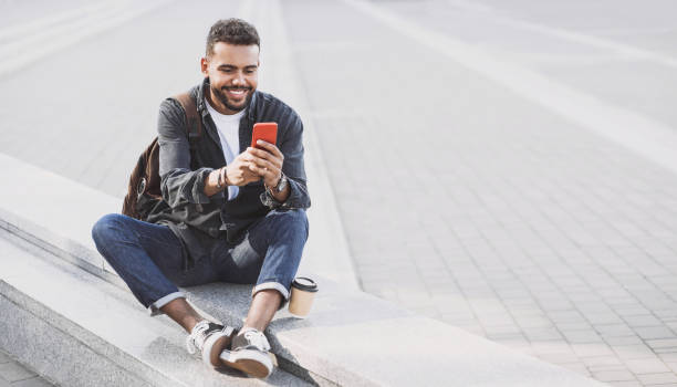 istock Cheerful young man using smart phone on a city street 1186351786