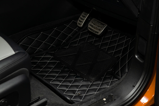 Clean black leather car floor mats with diamond stitching and gas pedals and brakes in the workshop for the detailing vehicle after dry cleaning