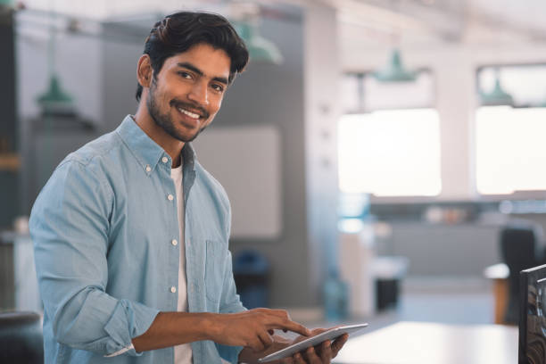istock Smiling young businessman using a digital tablet in an office 1186356589