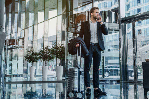 viajante de negócio masculino que está e que fala no telefone móvel no corredor do aeroporto - airport lounge airport one person bag - fotografias e filmes do acervo