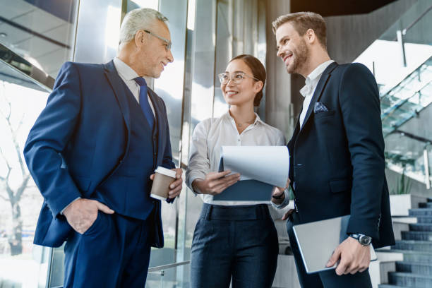 Smiling business people discussing over documents in office lobby
