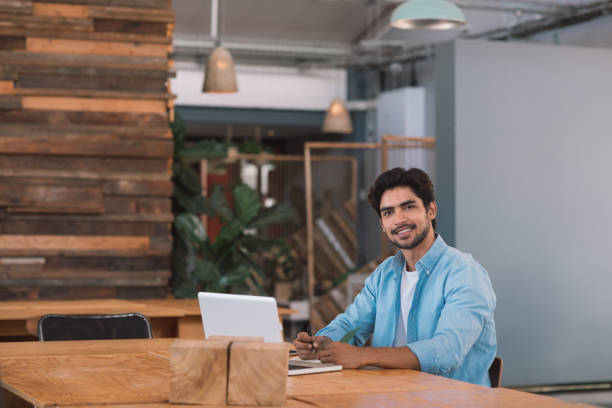 istock Smiling young businessman using a laptop in an office 1186358935