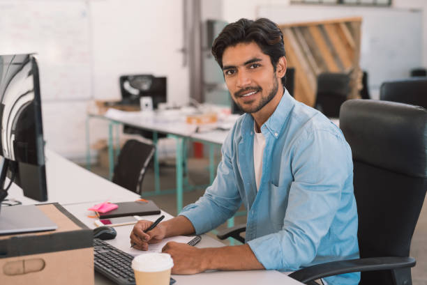 istock Smiling young businessman working on a computer in an office 1186359306