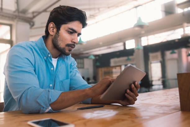 istock Young businessman sitting at a table working on a tablet 1186359772