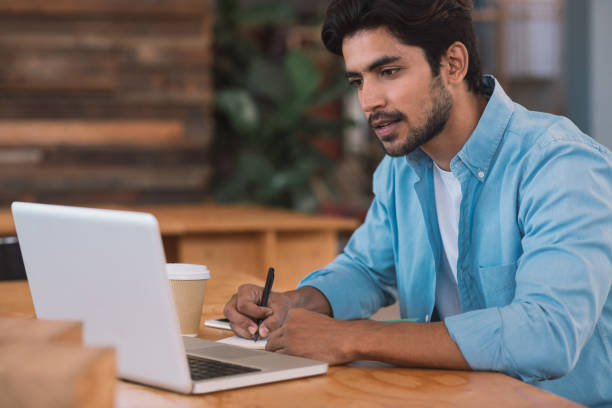 istock Young businessman working on a laptop and taking notes 1186362649