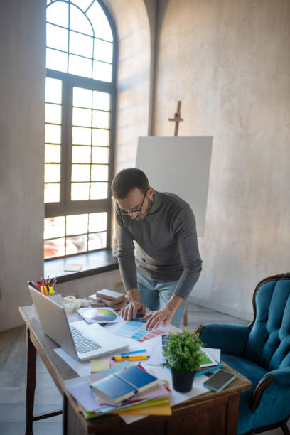 istock Interior designer standing near table having a lot of tasks 1186364281