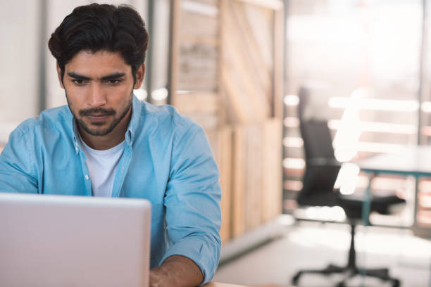 istock Young businessman sitting in an office using a laptop 1186365136