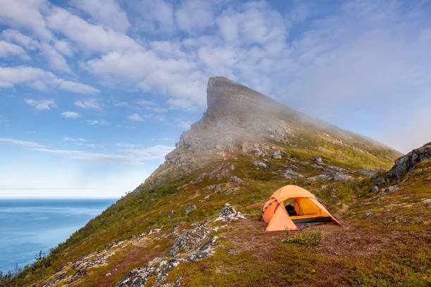 Tent on mountain ridge over clouds adventure journey traveling outdoor in Norway active vacations sunset Segla mountain, Senja.