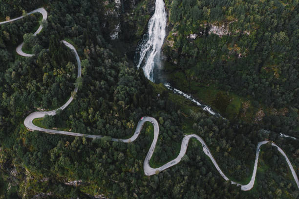 Scenic aerial view of camper van near waterfall on the hairpin road in Norway