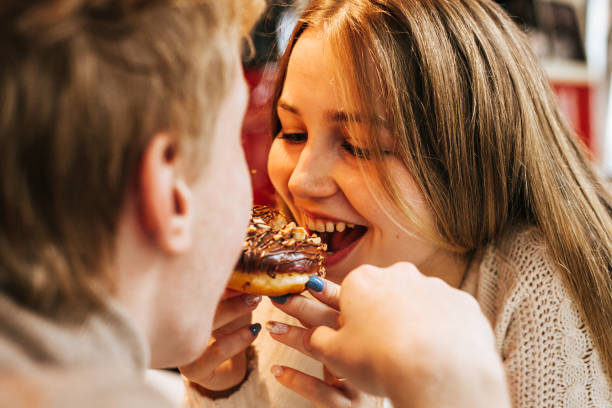 istock Young couple in a cafe eats a donut on a date 1186369189