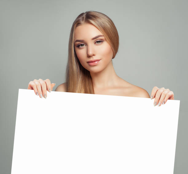 istock Young model woman with clear skin holding empty white card singboard 1186370308