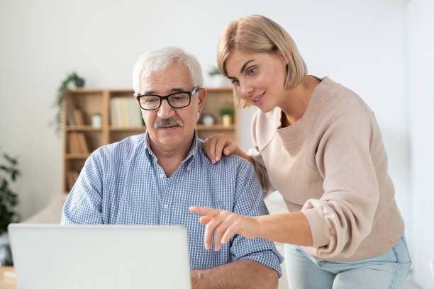 istock Young woman pointing at laptop display while explaining something to her father 1186371692