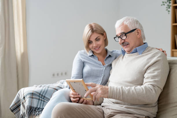 istock Senior man pointing at photo in frame while discussing it with young daughter 1186371884